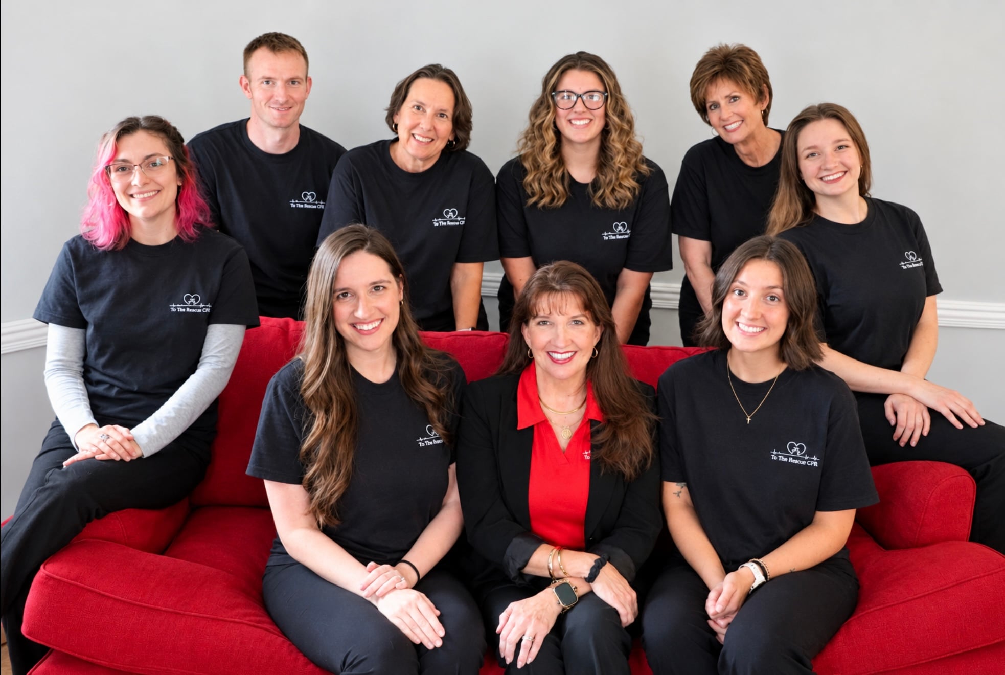 group photo of to the rescue cpr team posing together on a red couch smiling
